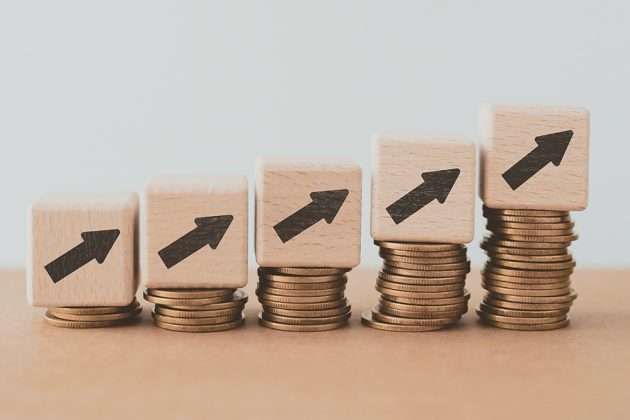 Five increasing stacks of coins, each topped with a wooden block with an upward arrow.