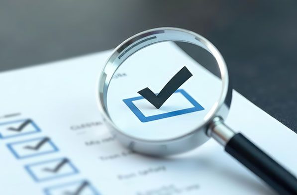 A magnifying glass enlarges a checked box on a checklist.