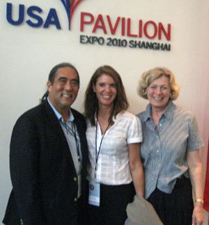 Three people pose beneath a USA Pavilion, Expo 2010 Shanghai sign.