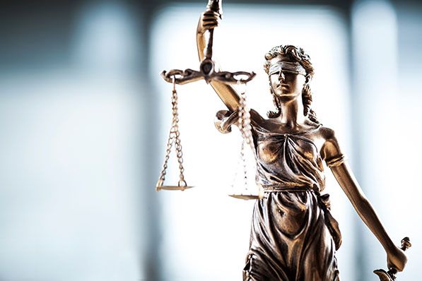 Bronze Lady Justice statue holding scales aloft.