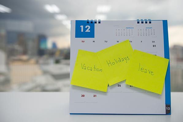 A December desk calendar with sticky notes reading Vacation, Holidays and leave.