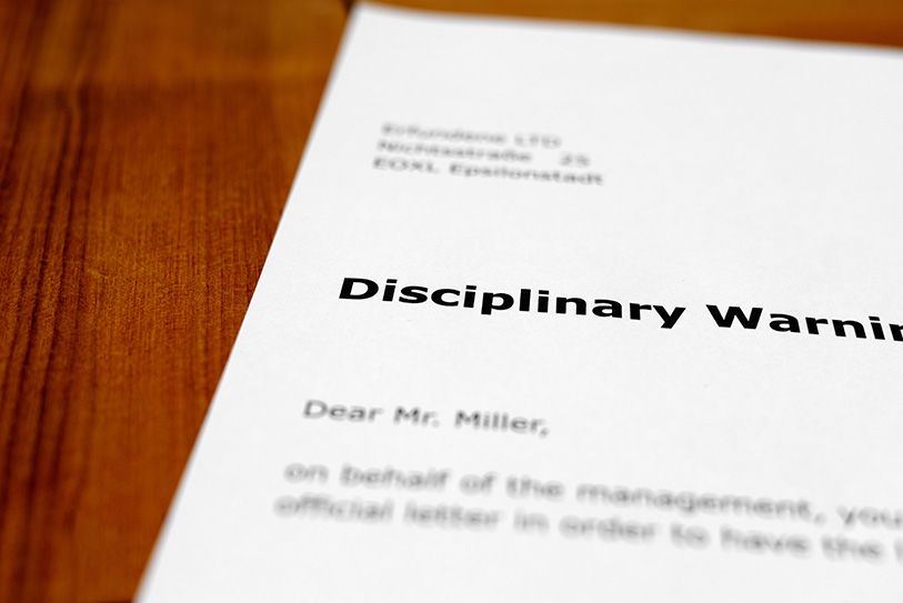 Close-up of a letter headed Disciplinary Warning on a wooden surface.