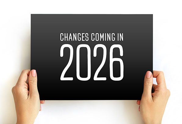 Two hands hold a black sign reading CHANGES COMING IN 2026.