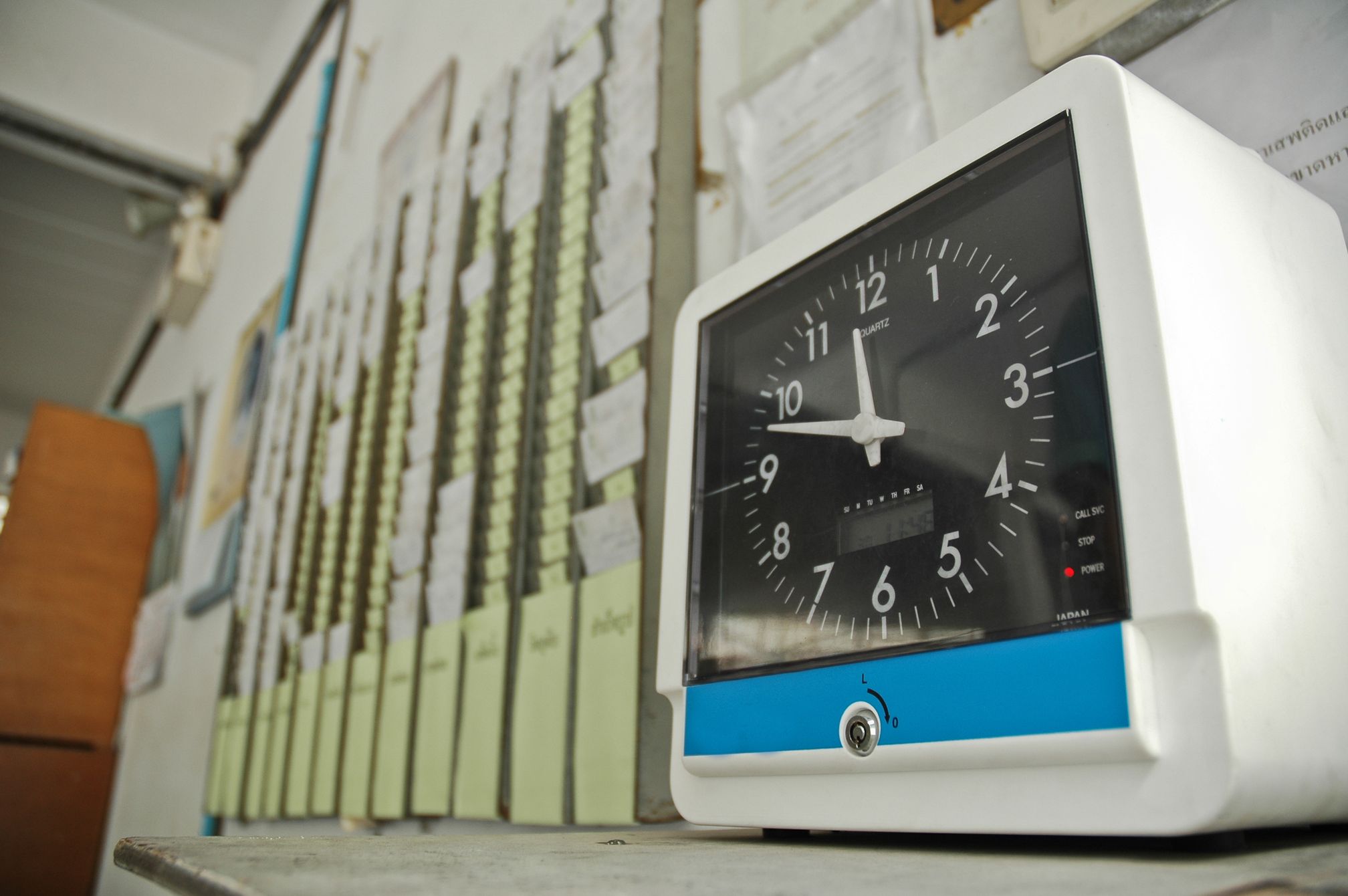 An employee time clock mounted beside rows of time cards.