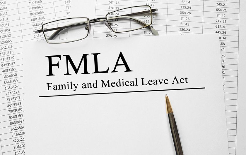 FMLA Family and Medical Leave Act document with glasses and a pencil on printed spreadsheets.