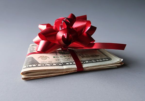 Folded dollar bills tied with a red ribbon and bow.