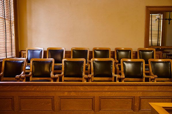 Rows of empty chairs in a wood-paneled courtroom jury box.