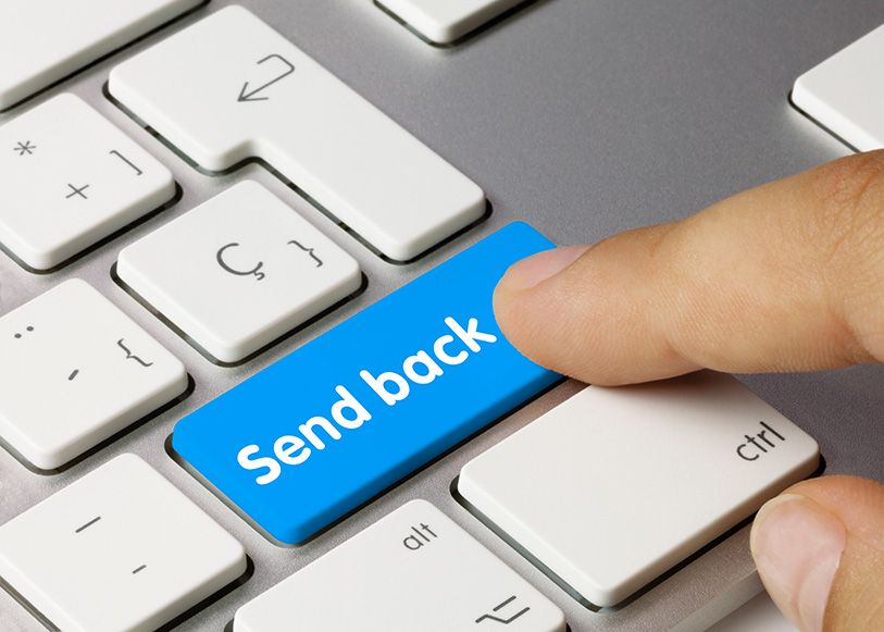 A finger presses a blue Send Back key on a computer keyboard.