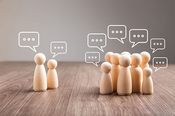 Wooden human figures stand in two groups beneath outlined speech bubbles.