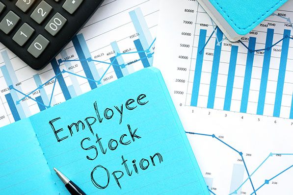 A blue note reading Employee Stock Option lies on financial charts beside a calculator.