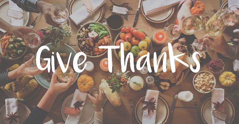 Give Thanks written over an overhead view of people sharing a meal around a full table.