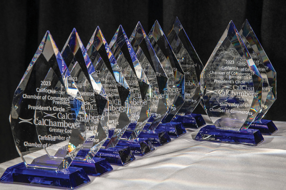 Rows of pointed glass CalChamber President’s Circle awards on blue bases.