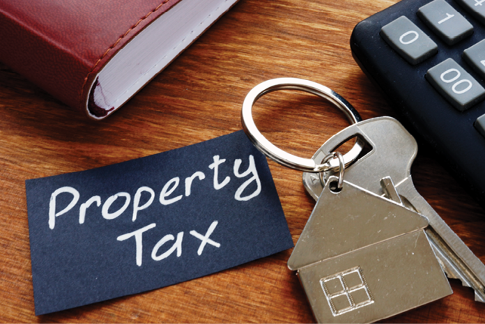 A Property Tax note beside house-shaped keys, a calculator and a notebook.