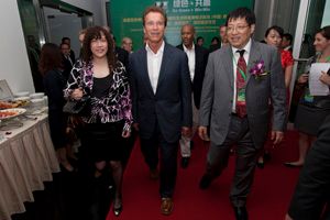 Three people in business attire walk along a red carpet at an indoor event.