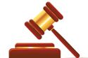 A brown and gold gavel resting on a sound block.