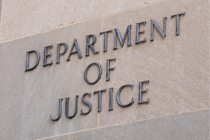DEPARTMENT OF JUSTICE lettering mounted on a stone building wall.