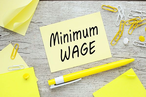 Yellow sticky note with "Minimum WAGE" written on it.