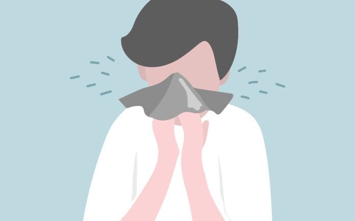 Illustration of a person sneezing into a tissue against a pale blue background.