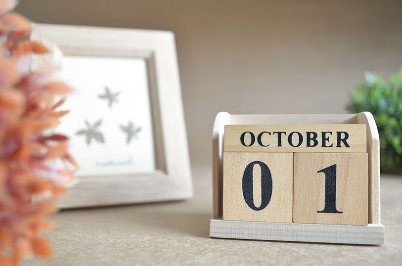 A wooden block calendar displays OCTOBER 01 on a table.