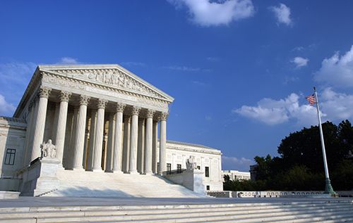 The U.S. Supreme Court building and broad steps beneath a blue sky with scattered clouds.