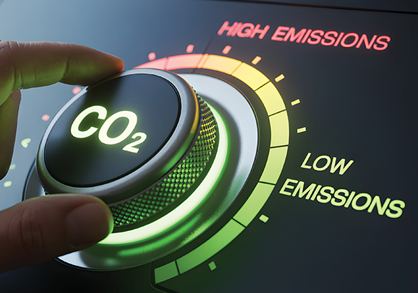 A hand turns a CO2 dial between high and low emissions settings.