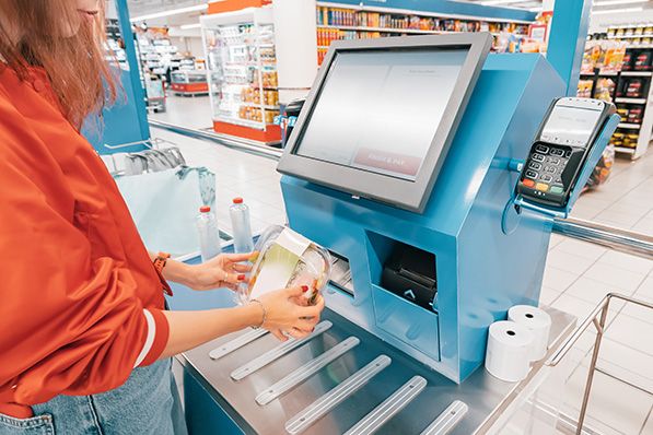 A shopper scans a packaged item at a supermarket self-checkout station.