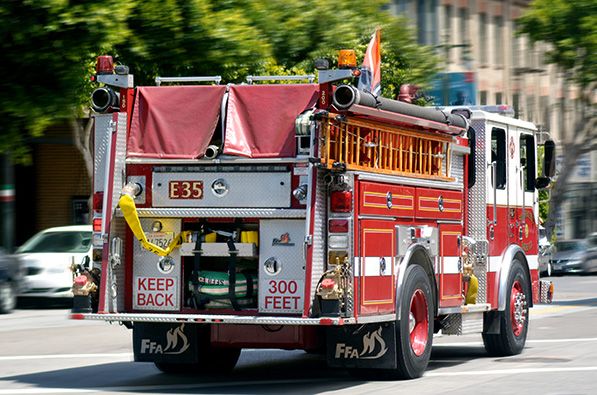 A red fire engine drives along a city street.