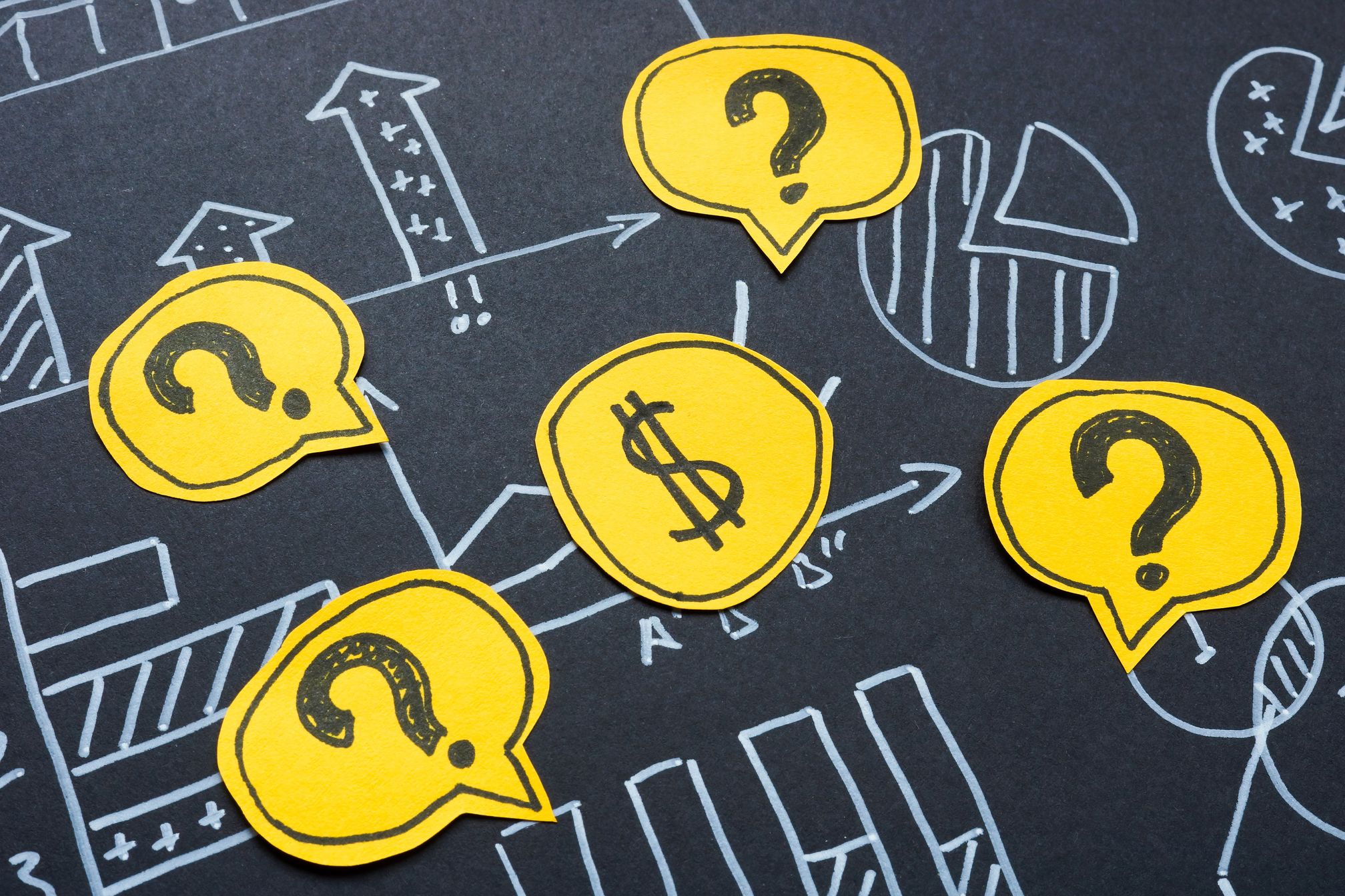 Yellow speech bubbles with question marks and a dollar sign over chalk-drawn charts.
