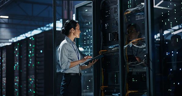 Woman inspecting servers with a tablet in a data center.