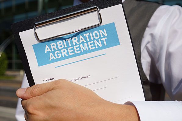 A person holds a clipboard with a document titled “Arbitration Agreement.”