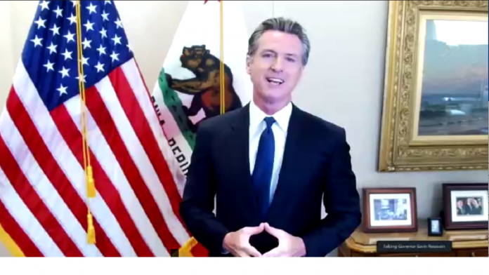 Gavin Newsom delivers a video address beside United States and California flags.