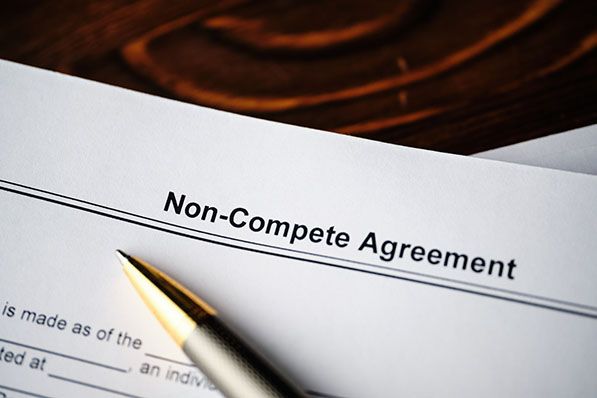 A fountain pen rests on a document headed Non-Compete Agreement.