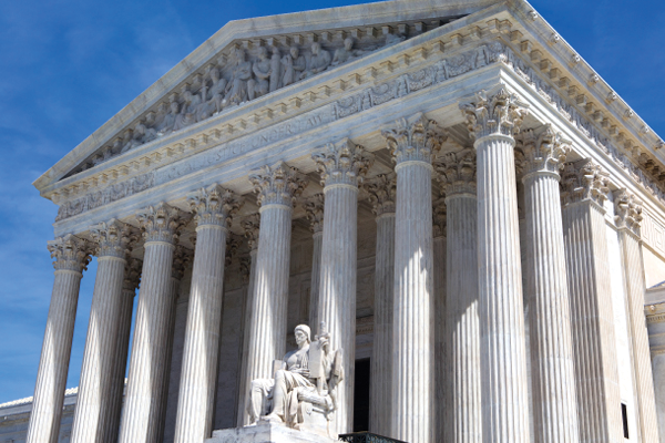 Low-angle view of the U.S. Supreme Court's white columns and sculpted pediment.