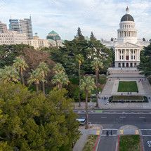 The California State Capitol dome rises beyond tree-lined streets and park grounds.