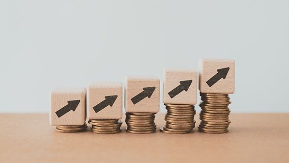 Increasing stacks of coins topped with wooden blocks displaying upward arrows.