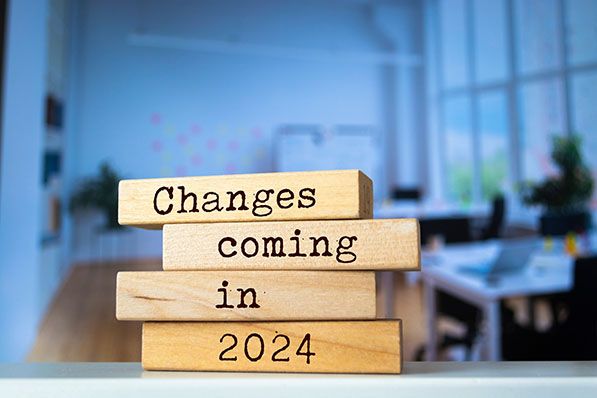 Stacked wooden blocks read 'Changes coming in 2024' in front of a blurred office.