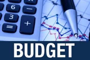 Budget lettering beneath a calculator, pen and financial line charts.