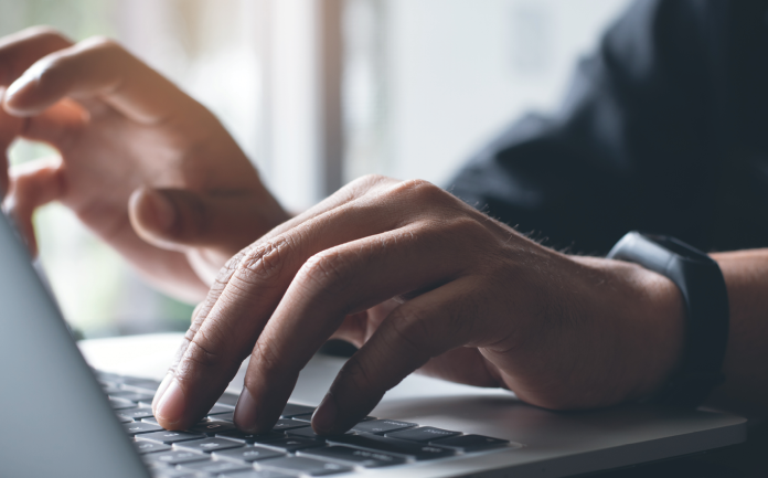 Close-up of hands typing on a laptop keyboard.