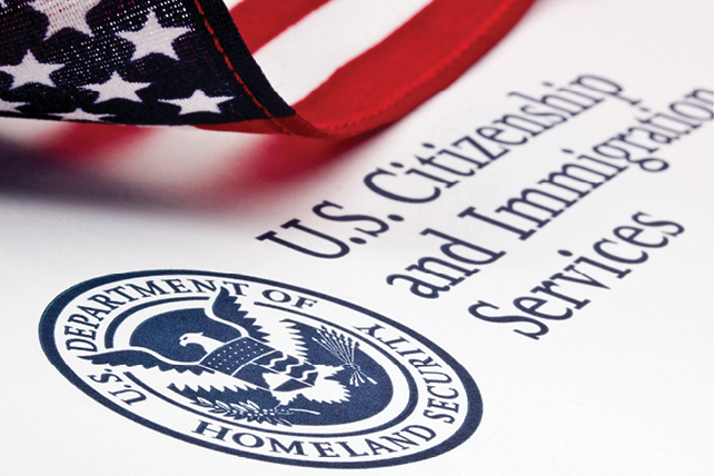 Close-up of U.S. Citizenship and Immigration Services lettering and Homeland Security seal beneath an American flag.