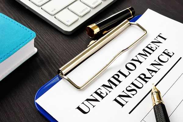 An Unemployment Insurance form on a clipboard beside a pen and keyboard.