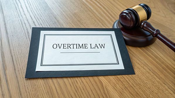 A document labeled OVERTIME LAW rests beside a judge's gavel on a wooden desk.