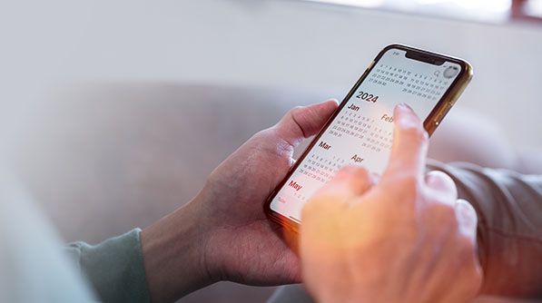 Hands use a smartphone displaying a yearly calendar.