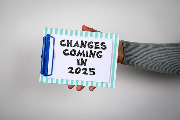 A hand holds a small board reading CHANGES COMING IN 2025.