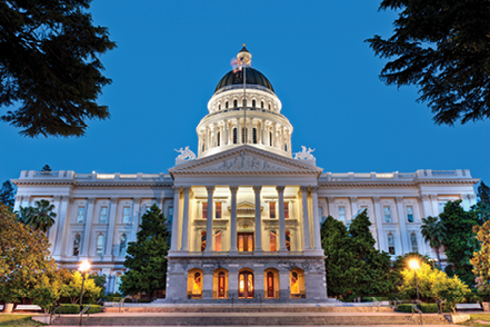 California State Capitol illuminated at dusk beneath a deep blue sky.