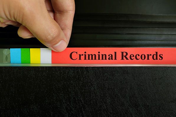 A hand pulls a red file tab labeled "Criminal Records" from a dark filing system.