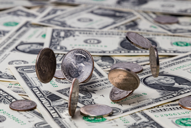 U.S. coins scattered across a surface covered with dollar bills.