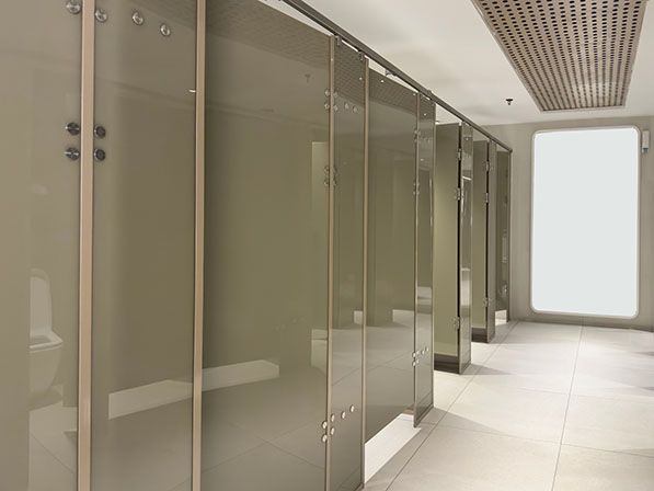 A row of enclosed restroom stalls in a bright tiled room.