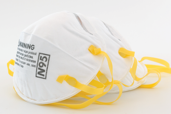 A stack of white N95 respirators with yellow straps.