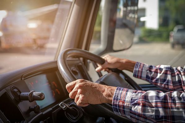 Close-up of a driver's hands holding a truck's steering wheel.
