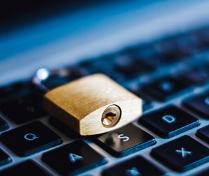 A small brass padlock rests on a laptop keyboard.